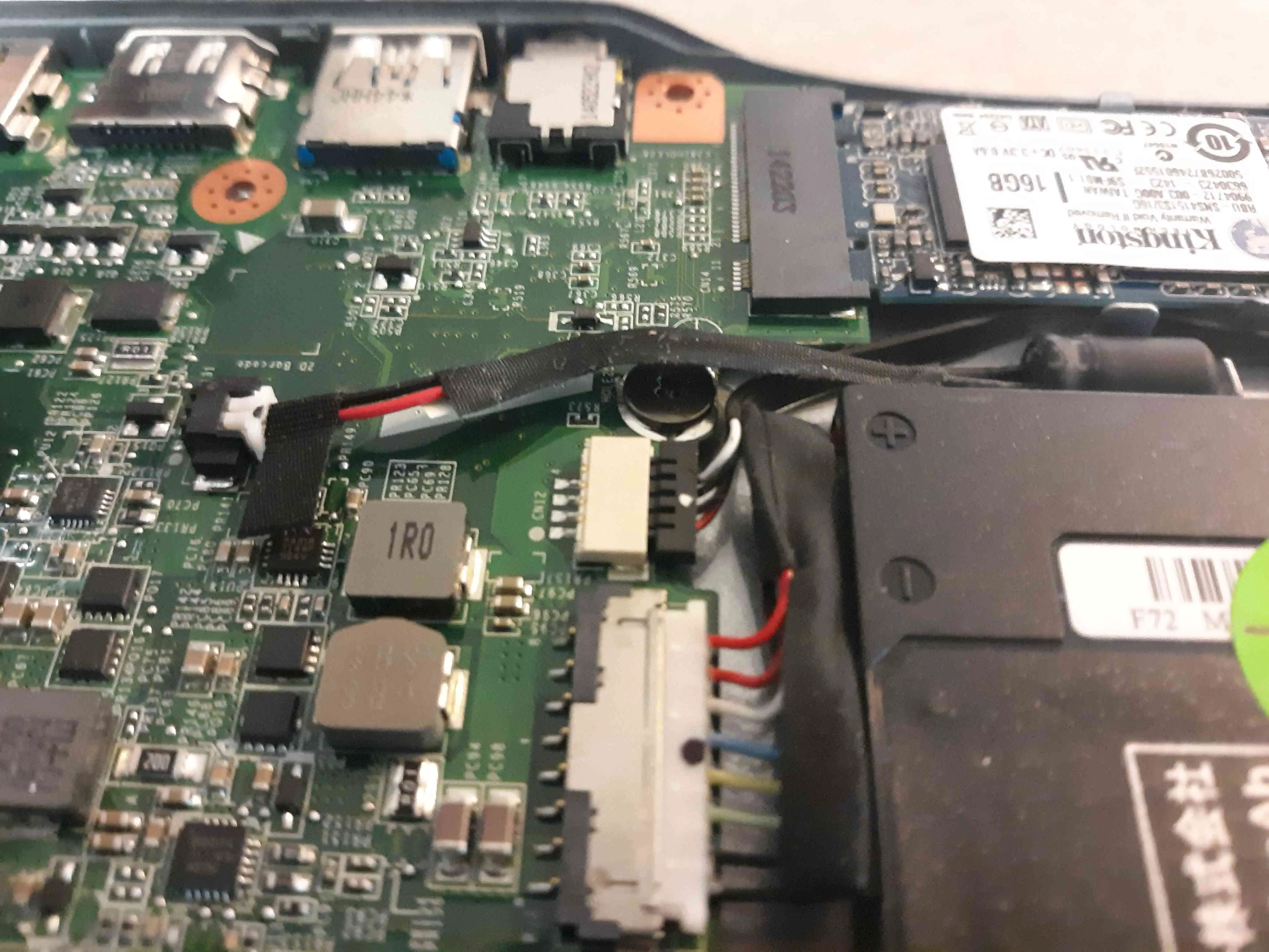 O parafuso de proteção contra gravação em um Chromebook Acer C720 está escondido sob um fio.
