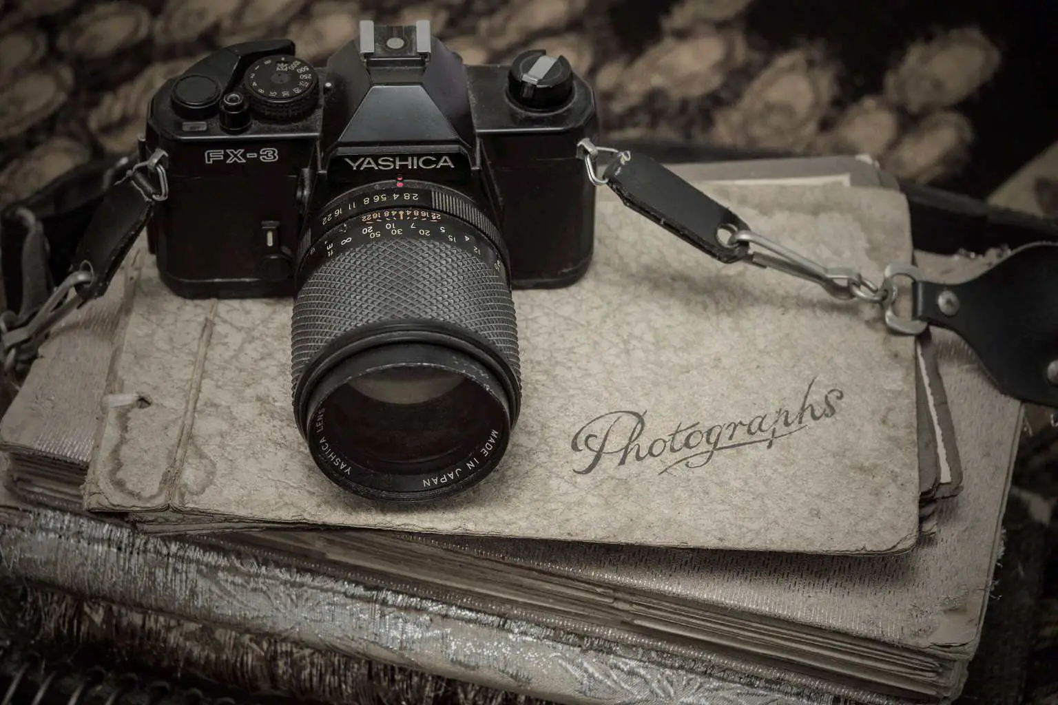 Uma câmera Yashica Single Refex Lens sobre um álbum de fotografias.