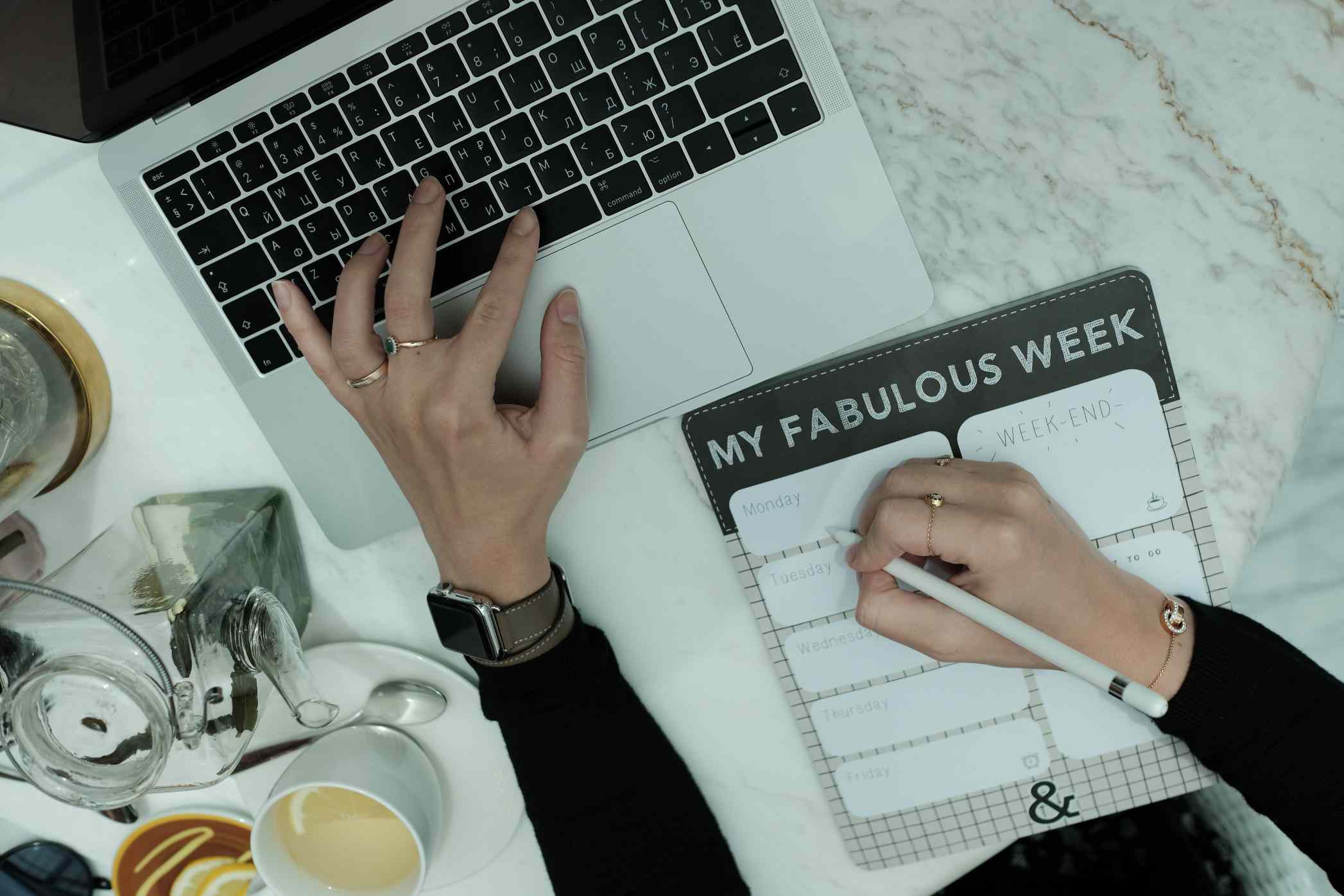 Uma mulher planejando sua semana com um computador e um calendário.