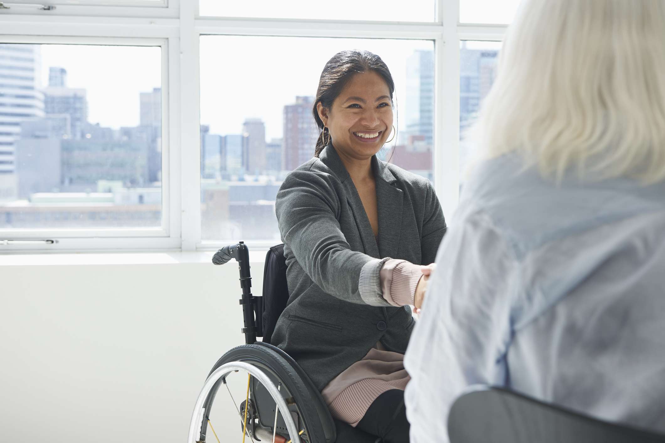 Mulher de negócios em cadeira de rodas apertando a mão de outra pessoa