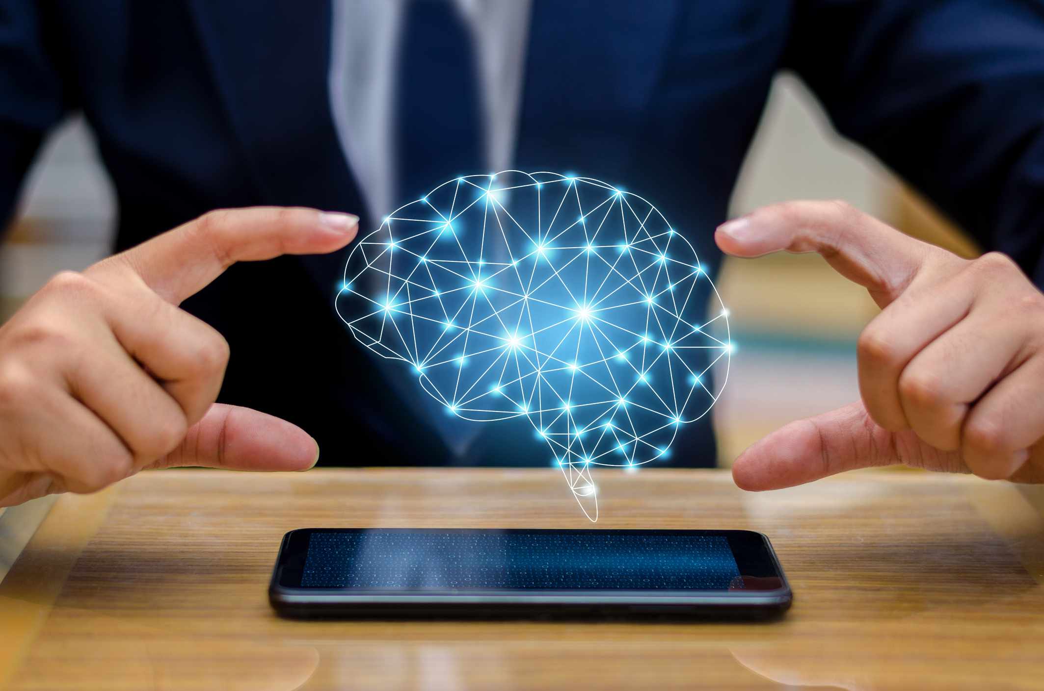 Imagem digital composta de um empresário usando um smartphone com um ícone de cérebro flutuando sobre ele.