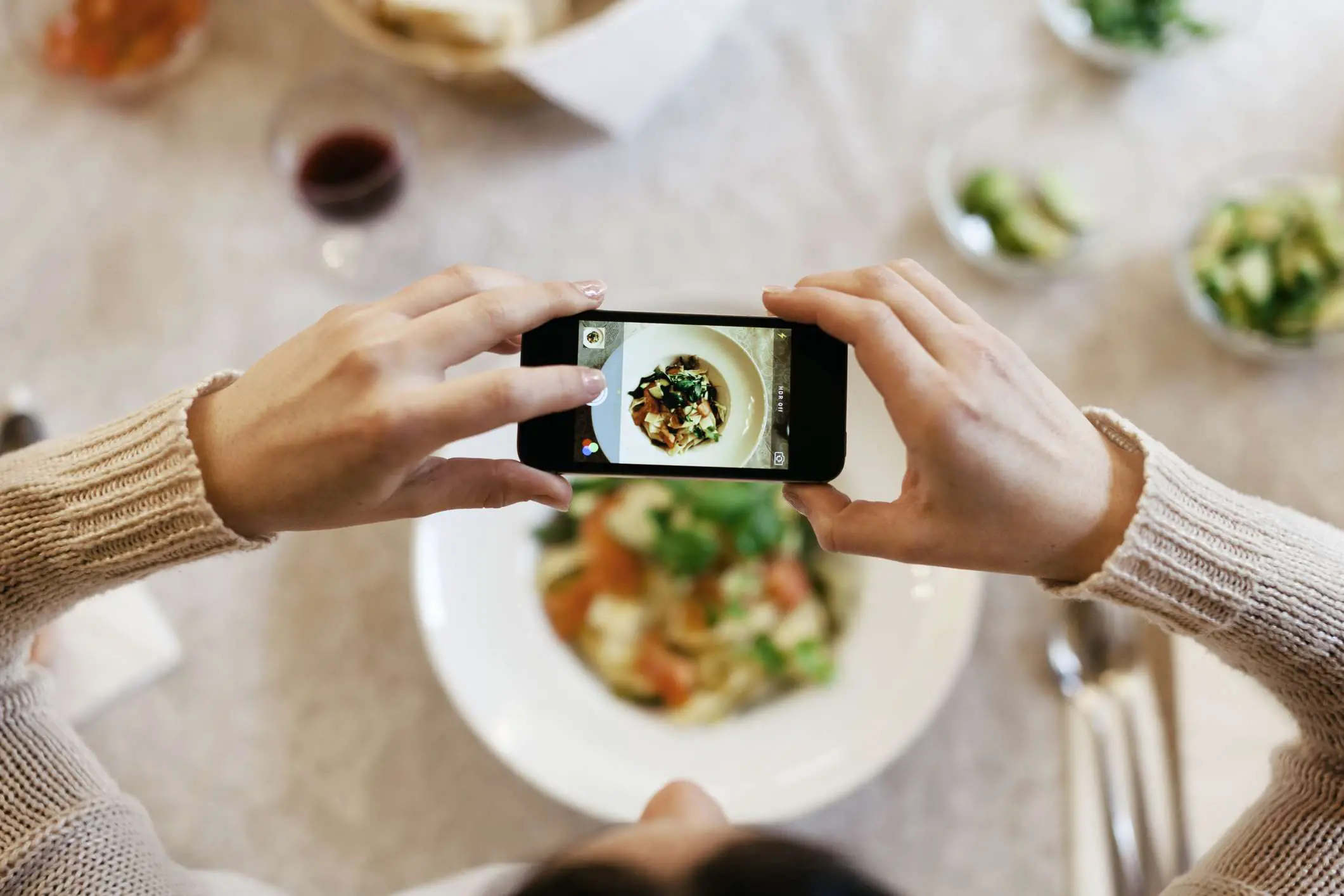 Uma imagem de alguém tirando uma foto de sua refeição com seu smartphone.