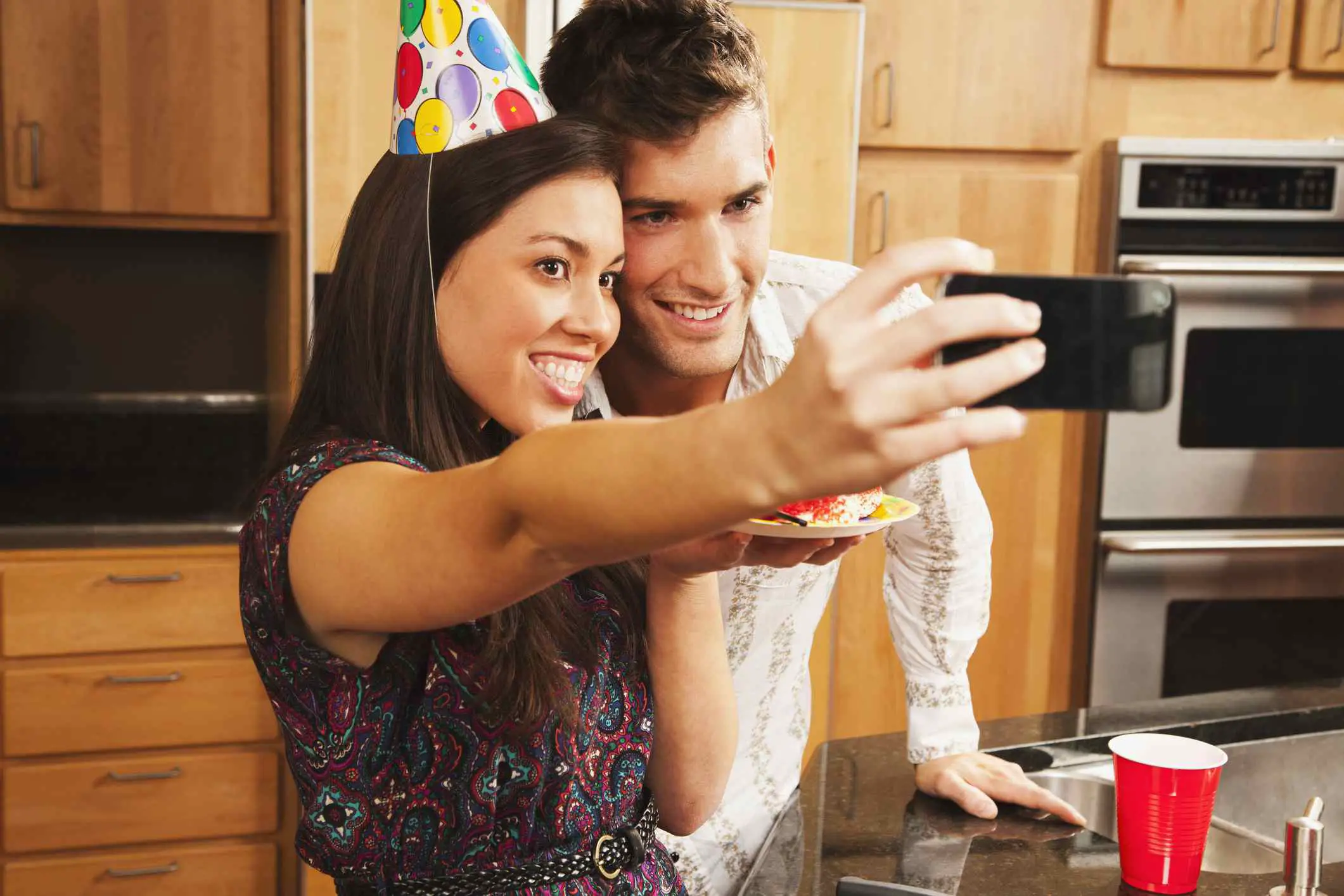 Uma imagem de um homem e uma mulher posando para uma selfie em uma festa de aniversário.
