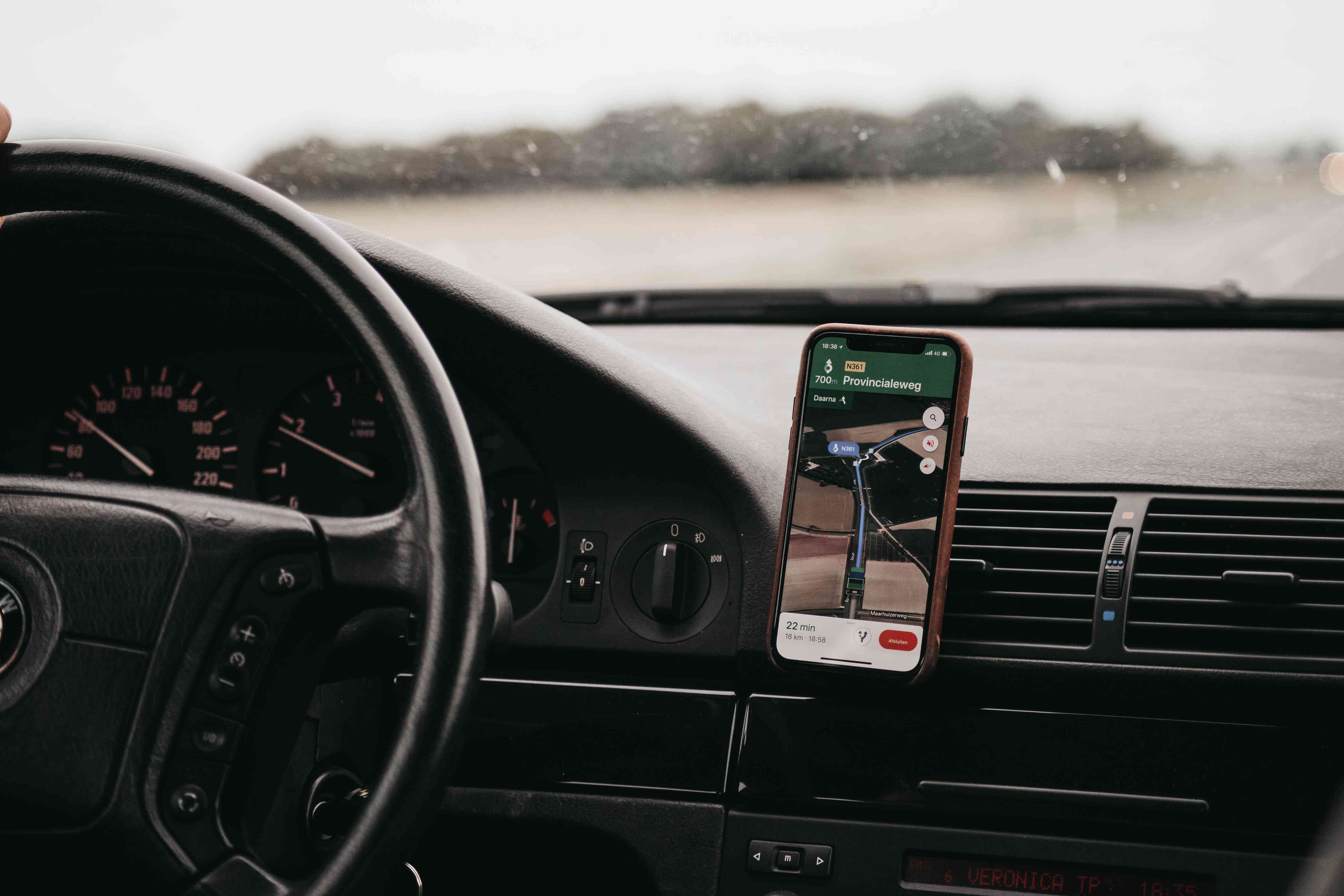 Um smartphone montado em uma saída de ar de automóvel exibindo um aplicativo de mapeamento. 