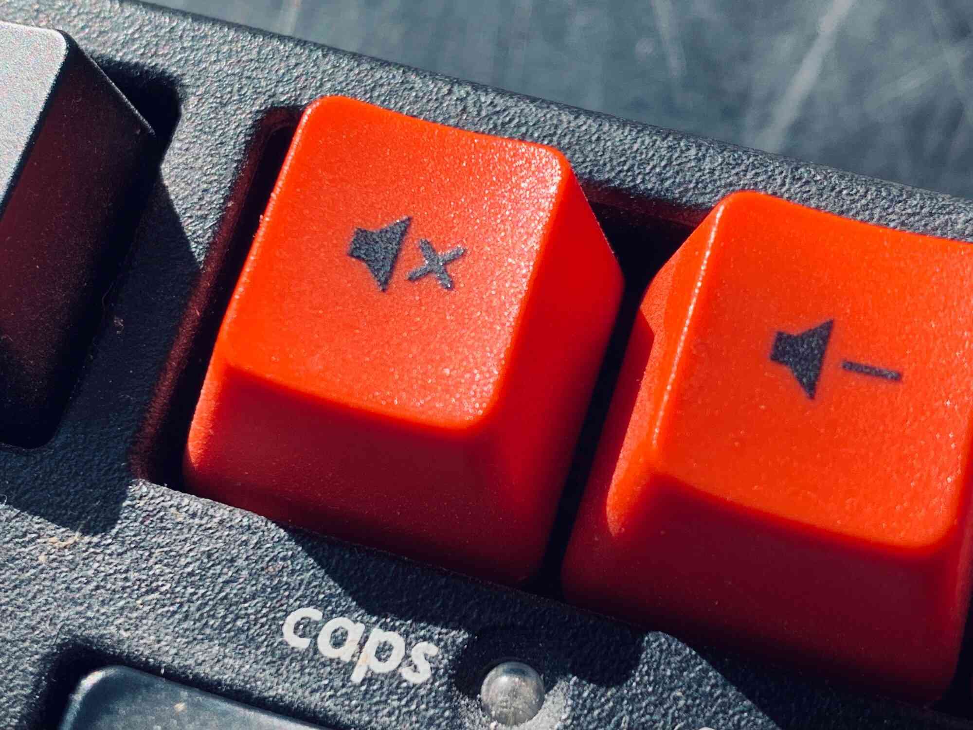 Imagem aproximada das teclas vermelhas de mudo e de volume para baixo de um teclado mecânico