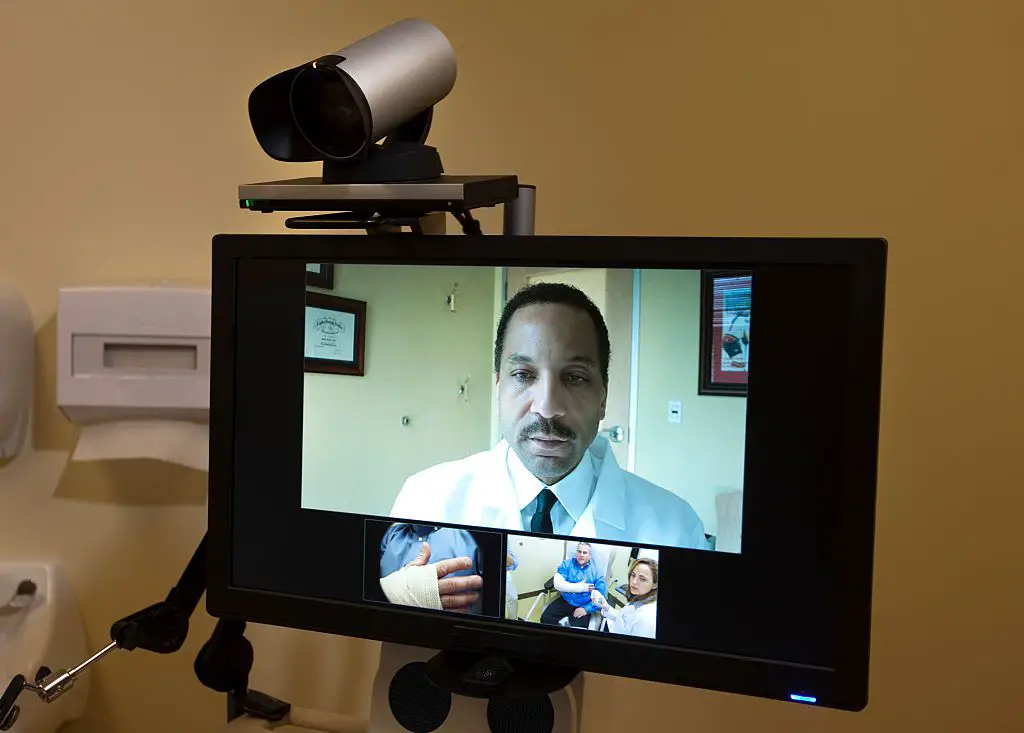 Dr. Maurice Cates, cirurgião ortopédico, conduz uma consulta ortopédica ao vivo remotamente por vídeo com um paciente