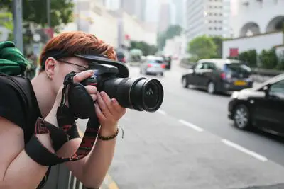 Mulher filmando uma DSLR na cidade