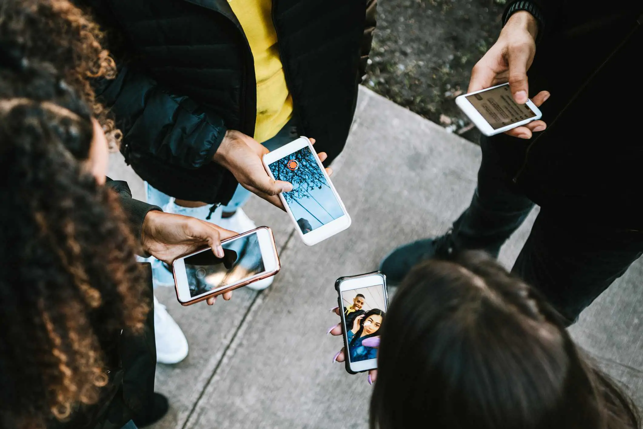 Um grupo de jovens adultos formando um círculo, todos olhando para seus smartphones.