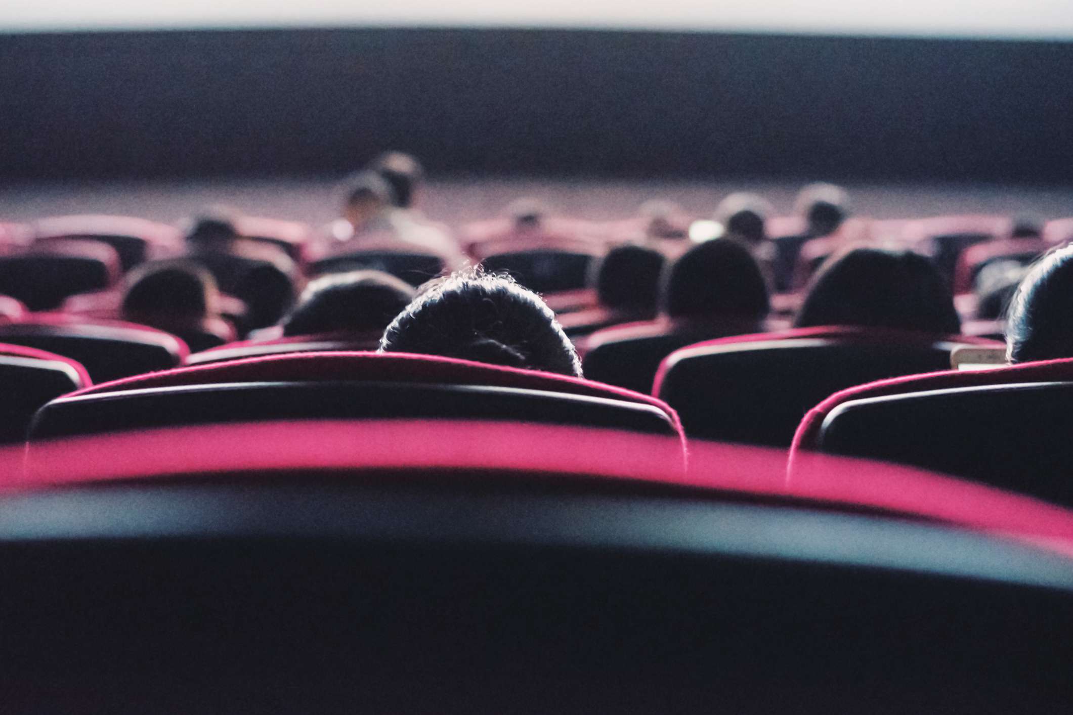 Uma visão traseira de pessoas sentadas em uma sala de cinema.