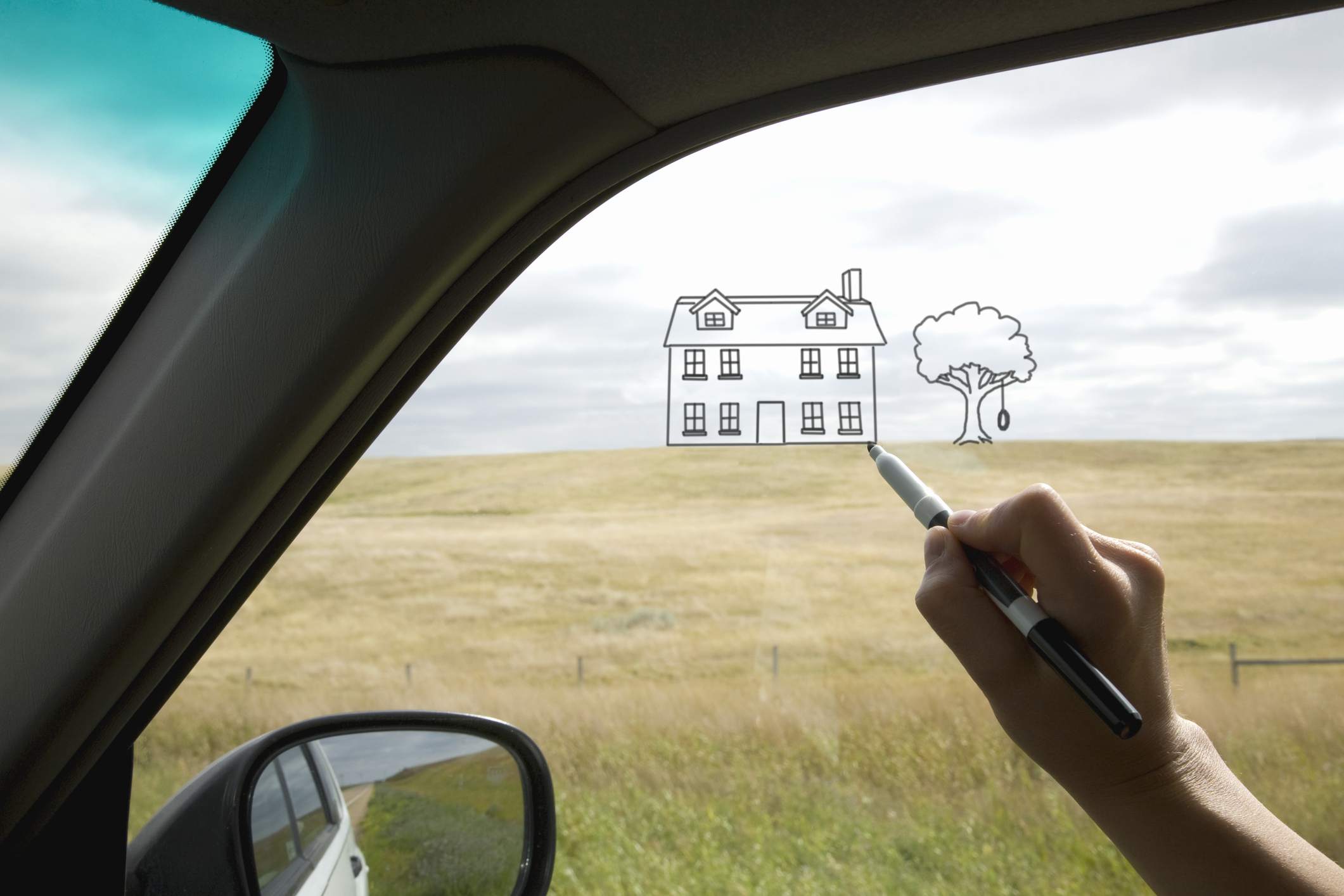 Uma pessoa desenhando uma casa na janela de um carro
