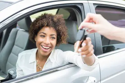 Uma mulher aceitando as chaves de um carro que comprou.