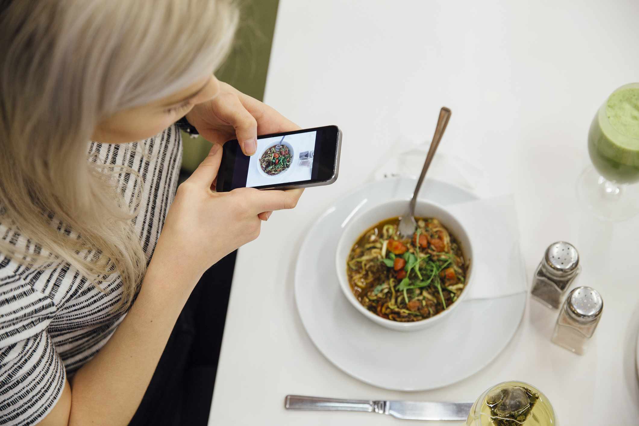 Pessoa tirando uma foto de sua refeição em um smartphone.