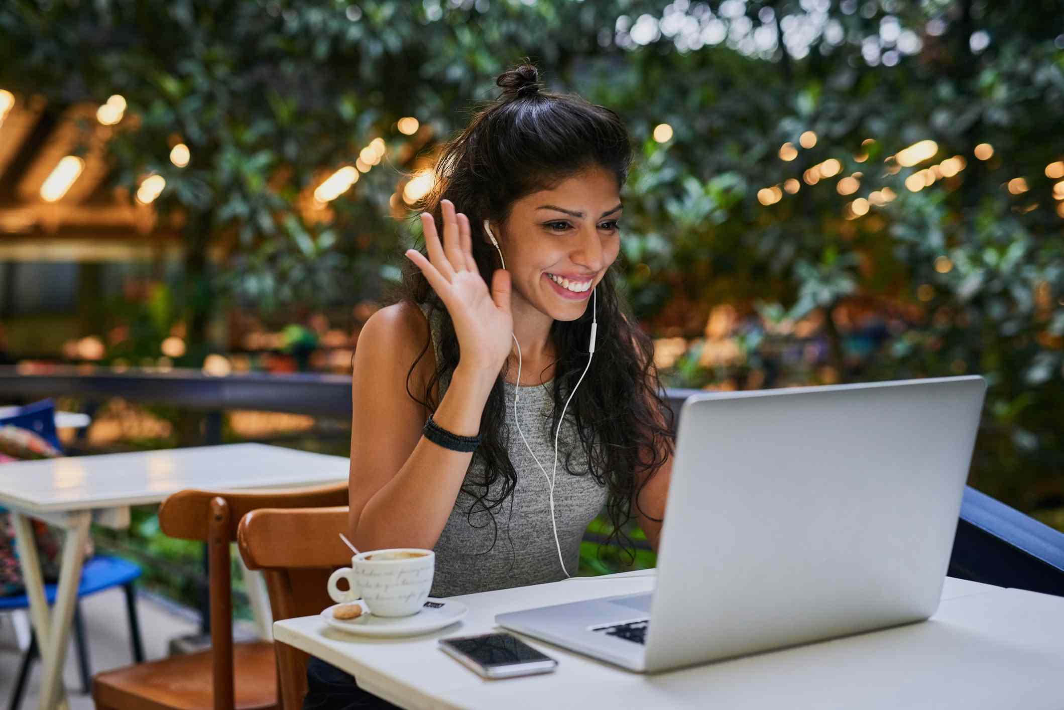 Gerente de mídia social fazendo uma videochamada no Facebook em um café com um laptop