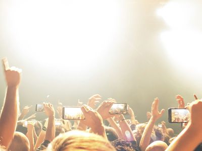 Uma multidão filmando um show em seus smartphones