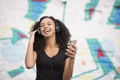 Adolescente ouvindo música no iPhone contra uma parede com grafite