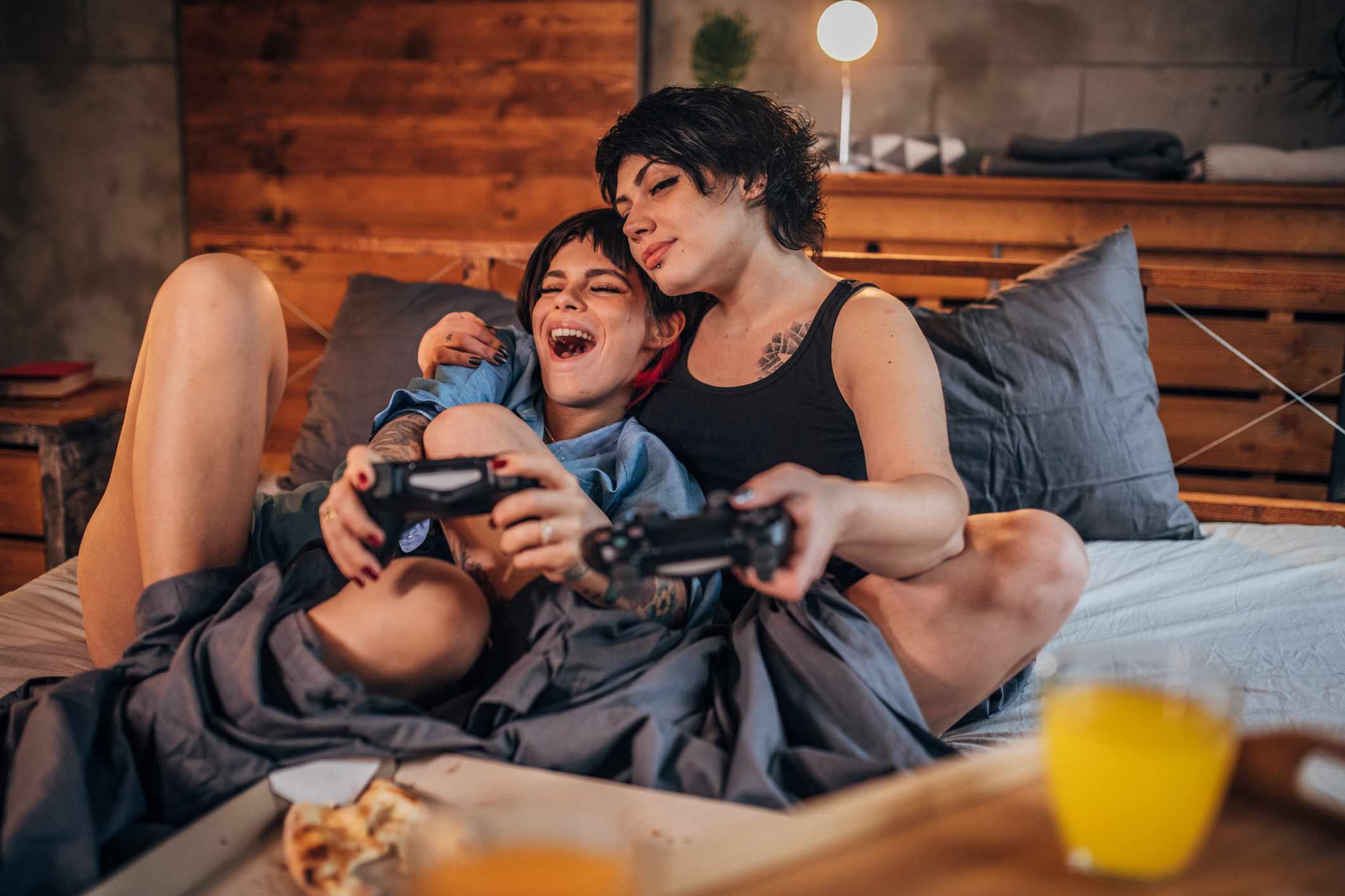 Um casal jogando videogame no quarto enquanto comia pizza. 