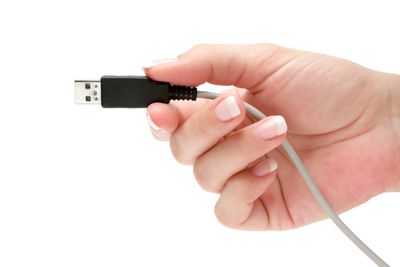 Uma mão segurando um cabo USB, isolado contra um fundo branco