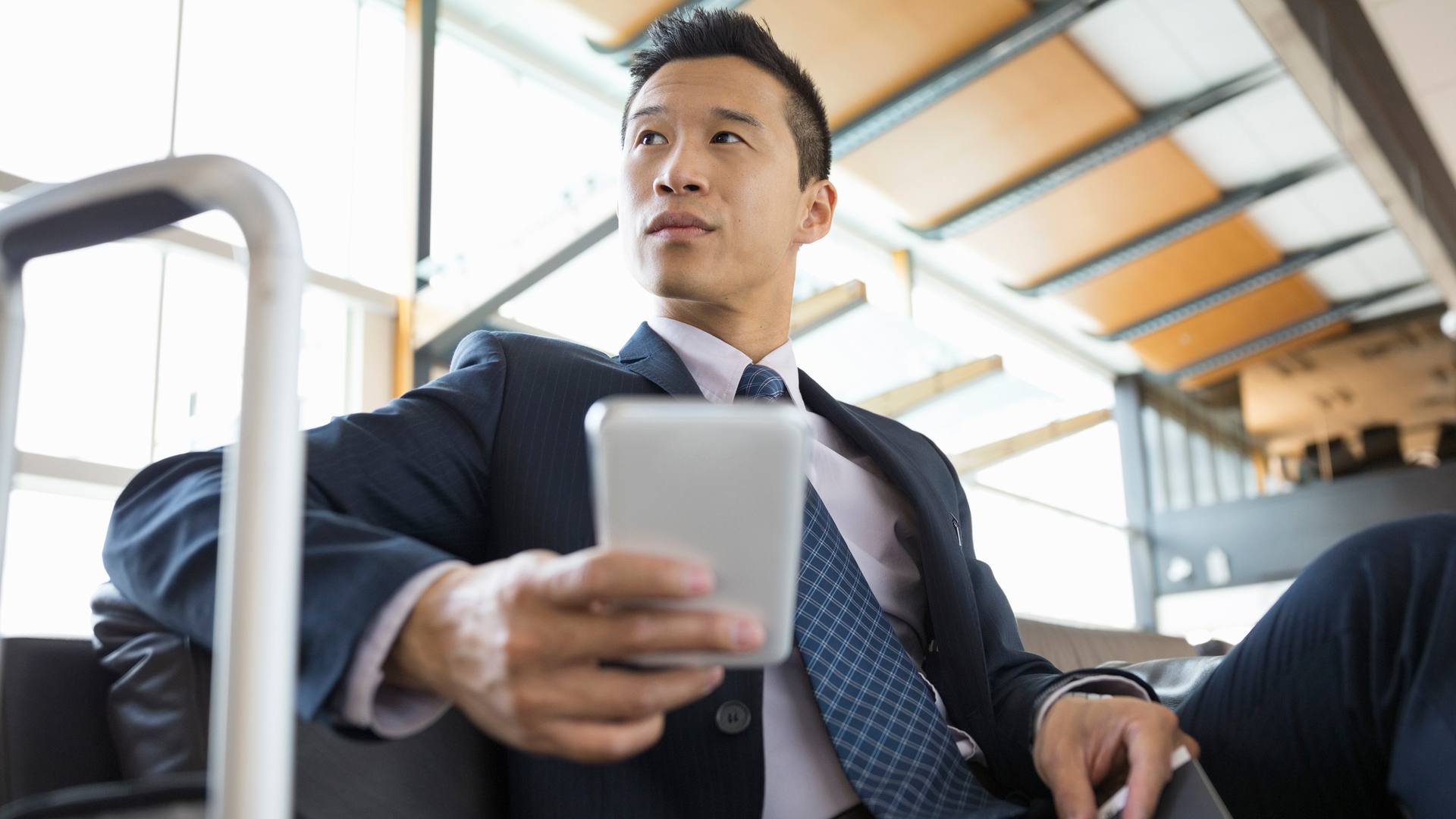 Homem de negócios asiático em viagem de negócios, verificando seu telefone com wi-fi portátil.