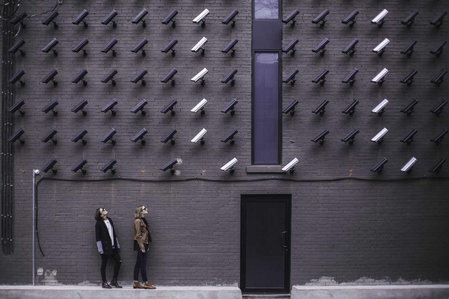 duas mulheres enfrentando câmeras de segurança montadas acima da porta