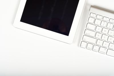 Tablet na mesa de escritório branca com teclado de computador e espaço de cópia