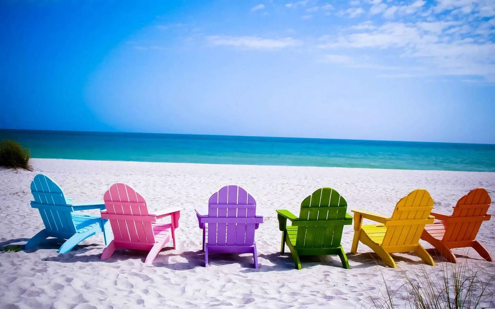 Papel de parede de praia gratuito com cadeiras coloridas em uma praia de areia branca