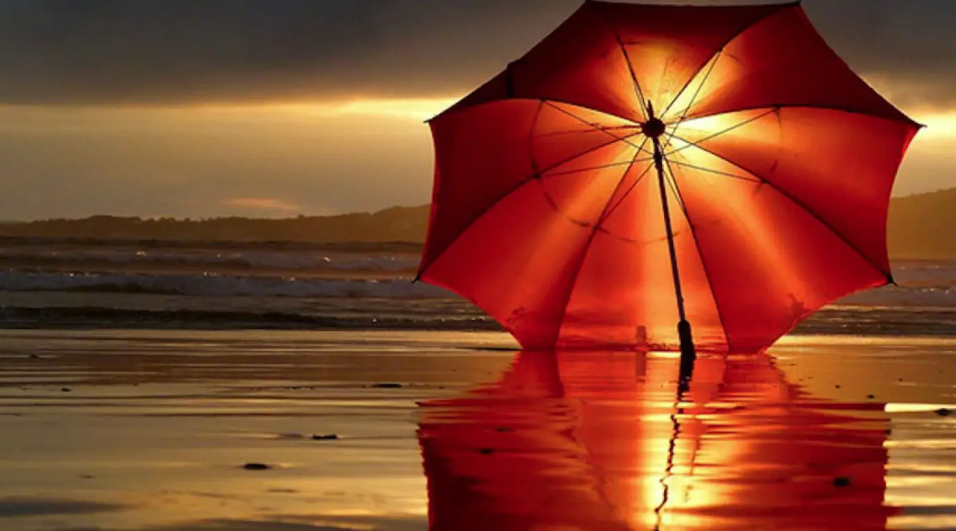 Papel de parede de praia gratuito com um guarda-sol vermelho ao pôr do sol