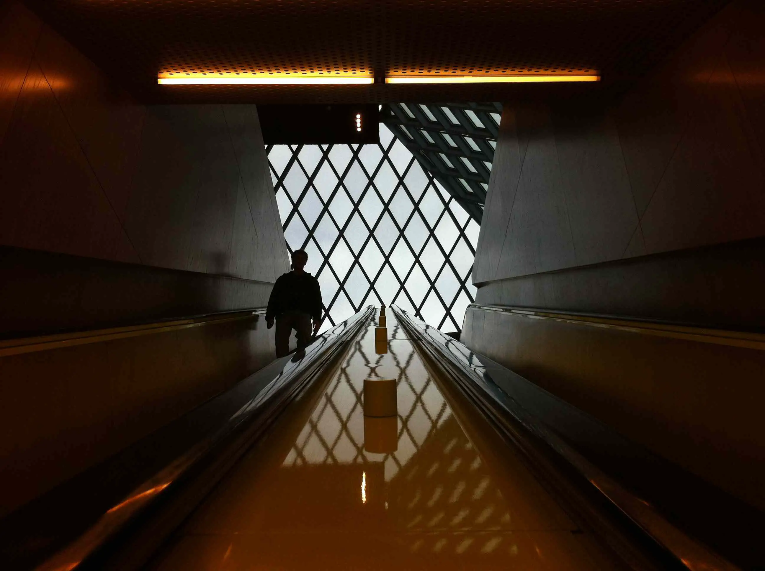 Homem descendo uma escada rolante em um corredor escuro