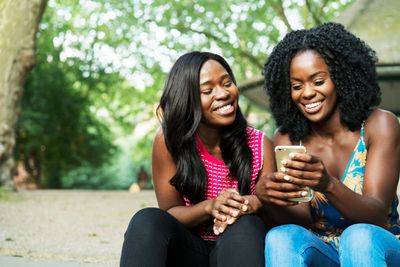Duas mulheres rindo e olhando para um iPhone