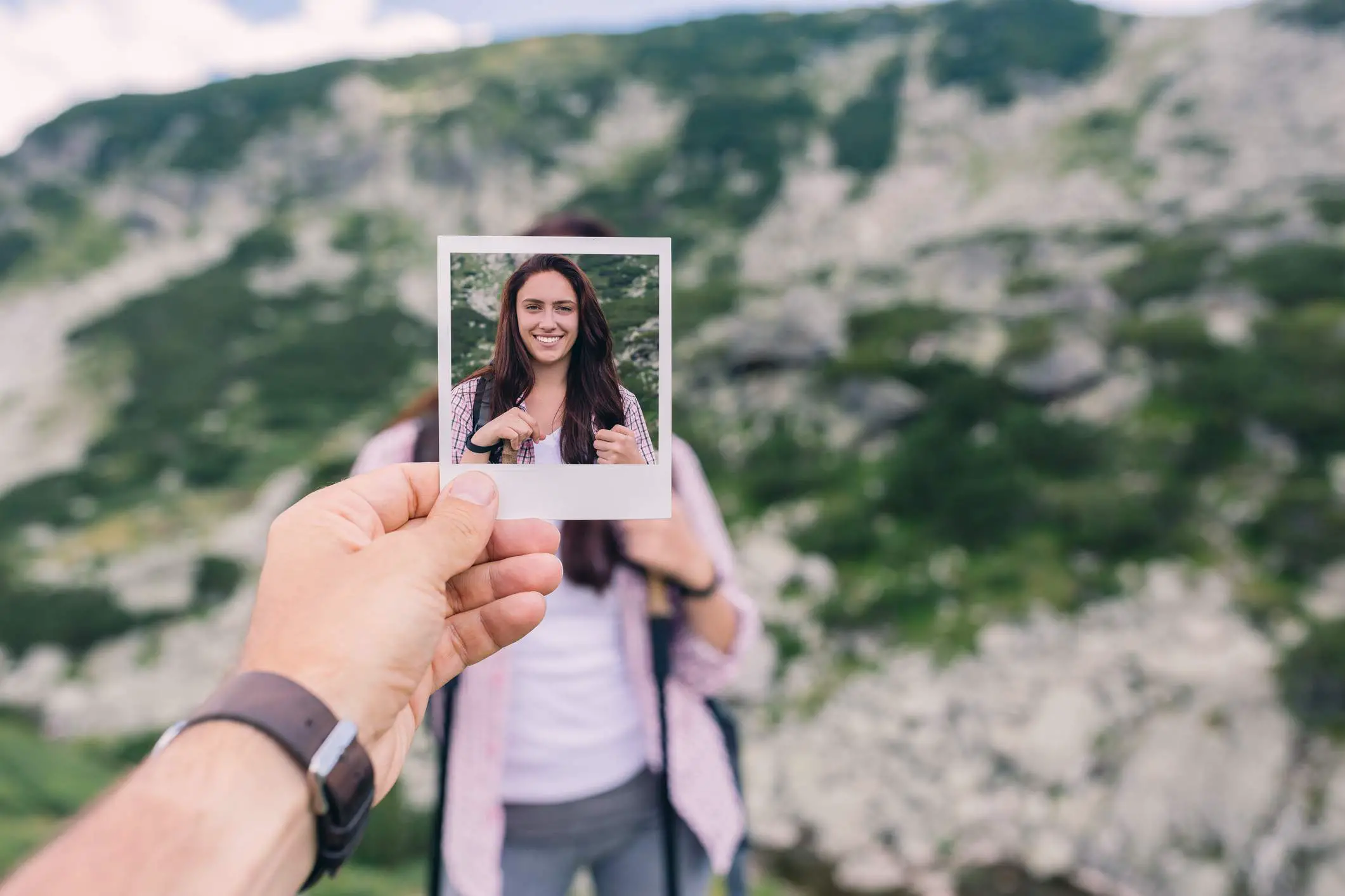Uma pessoa segurando uma fotografia na frente da pessoa na fotografia.