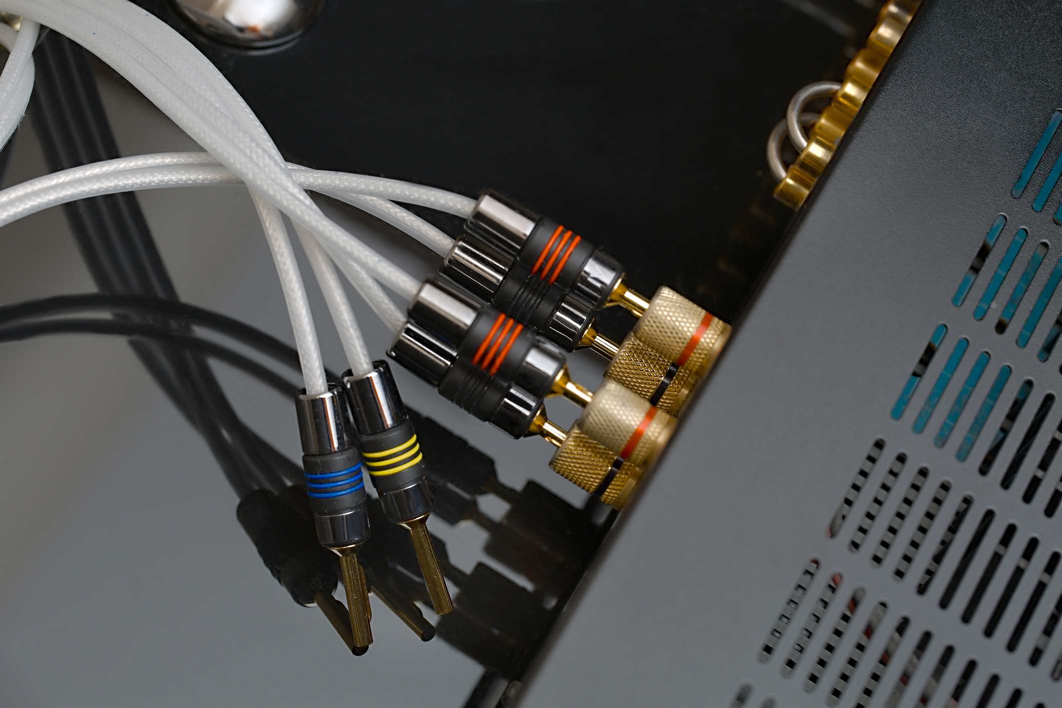 Parte traseira do amplificador ou receptor com cabos indo para os alto-falantes