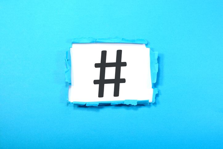 Sinal de hashtag mostrado em um papel azul rasgado.
