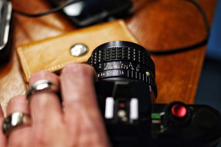 Uma mão segura uma câmera com a lente e o anel de foco exibidos de forma proeminente