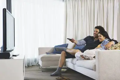 Um casal sentado em um sofá assistindo TV