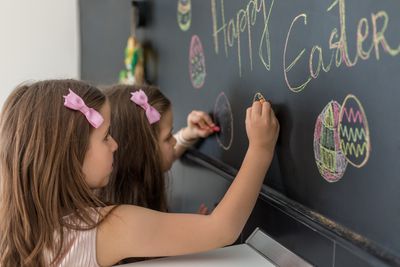 Crianças decorando um quadro-negro para a Páscoa semelhante a uma fonte de Páscoa