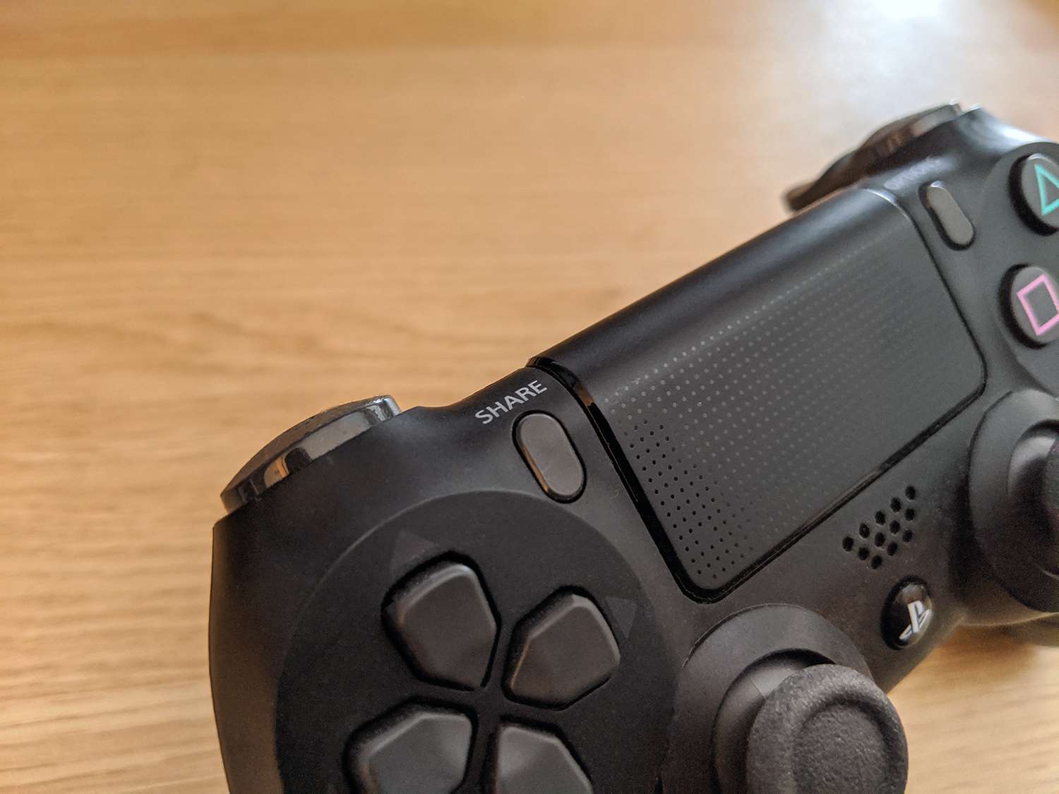 Close-up do botão Share em um controlador PS4.