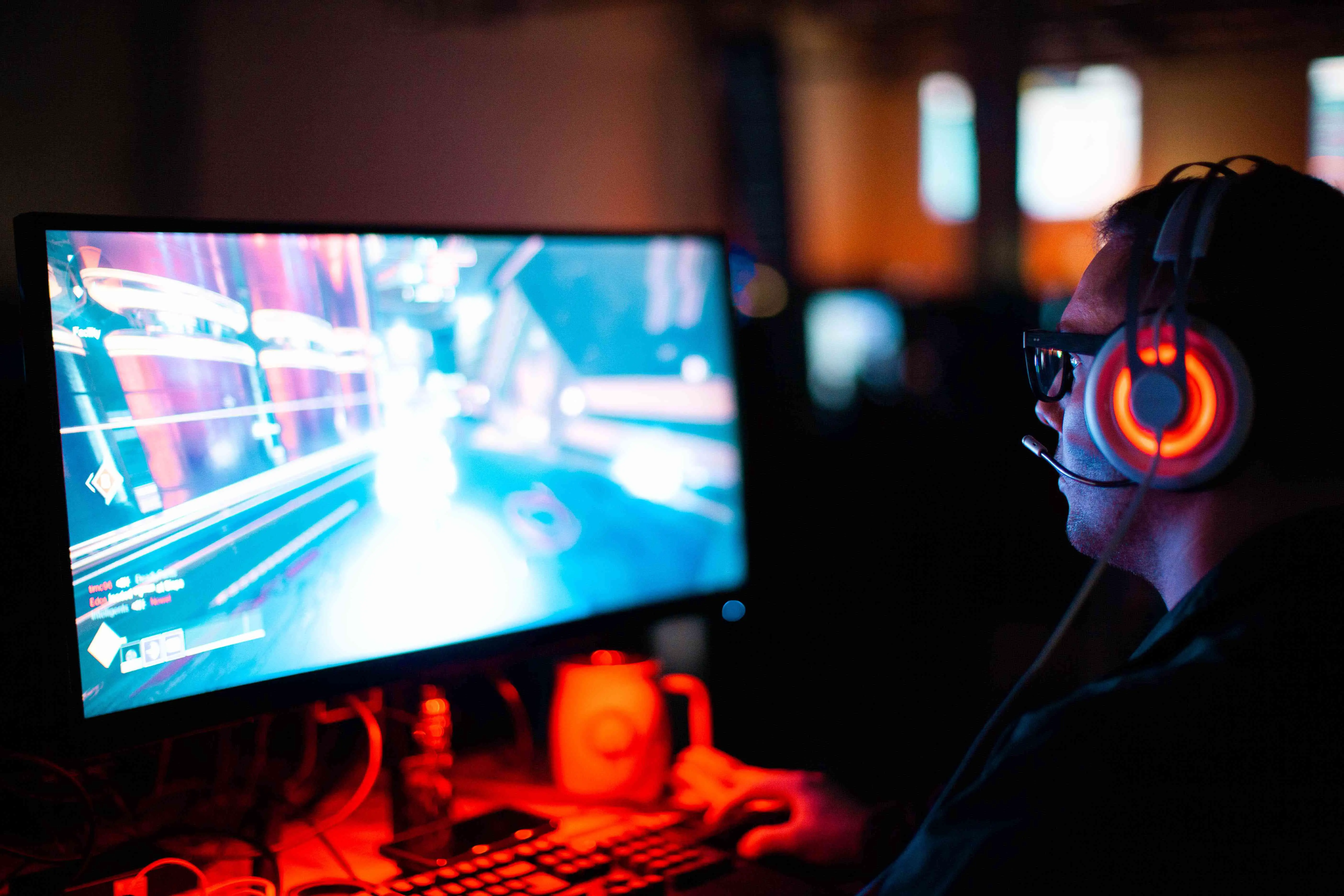 Um jogador jogando em um PC em uma sala mal iluminada.