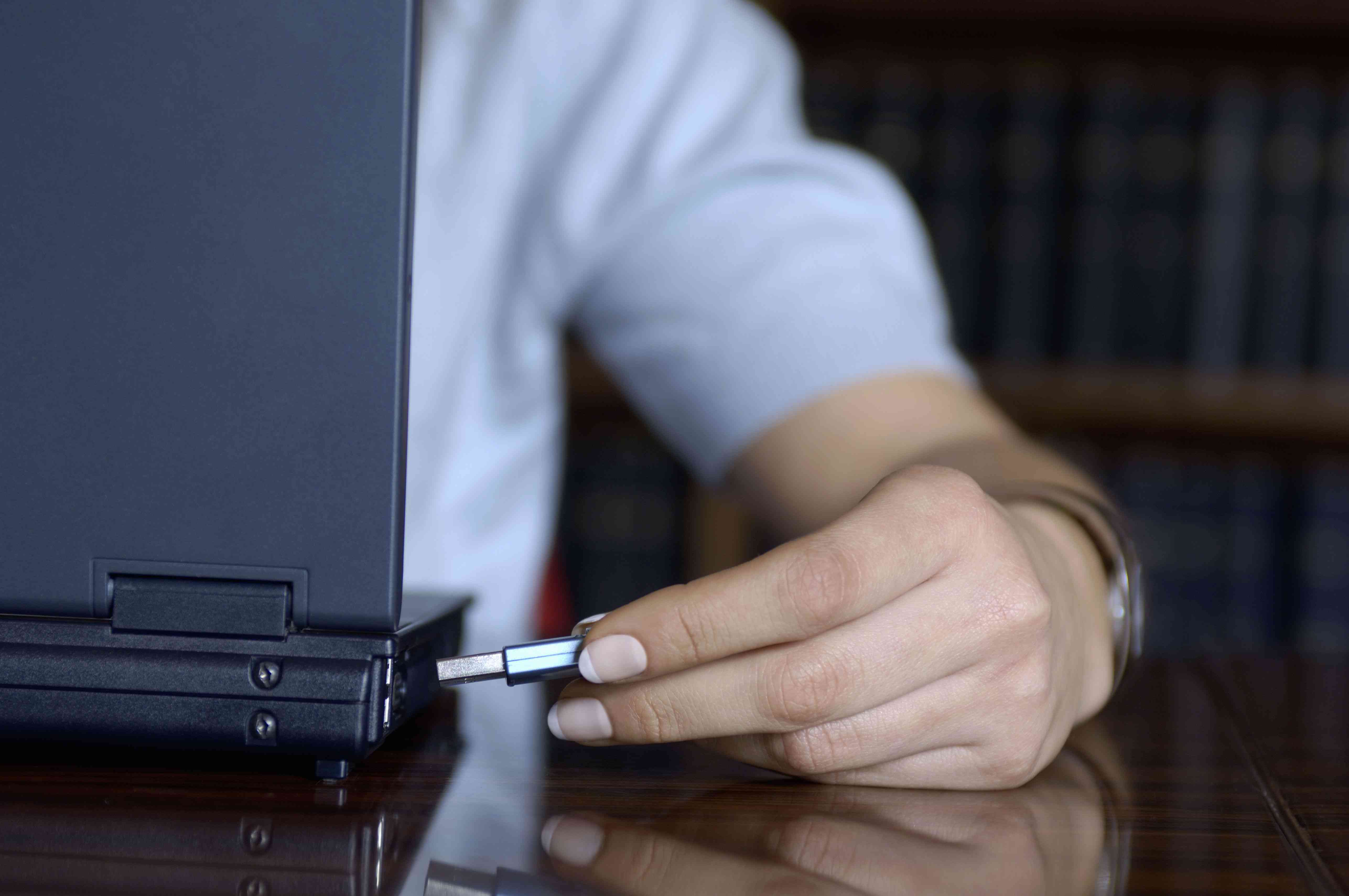 Mulher jovem usando um disco rígido USB portátil em um laptop, close-up