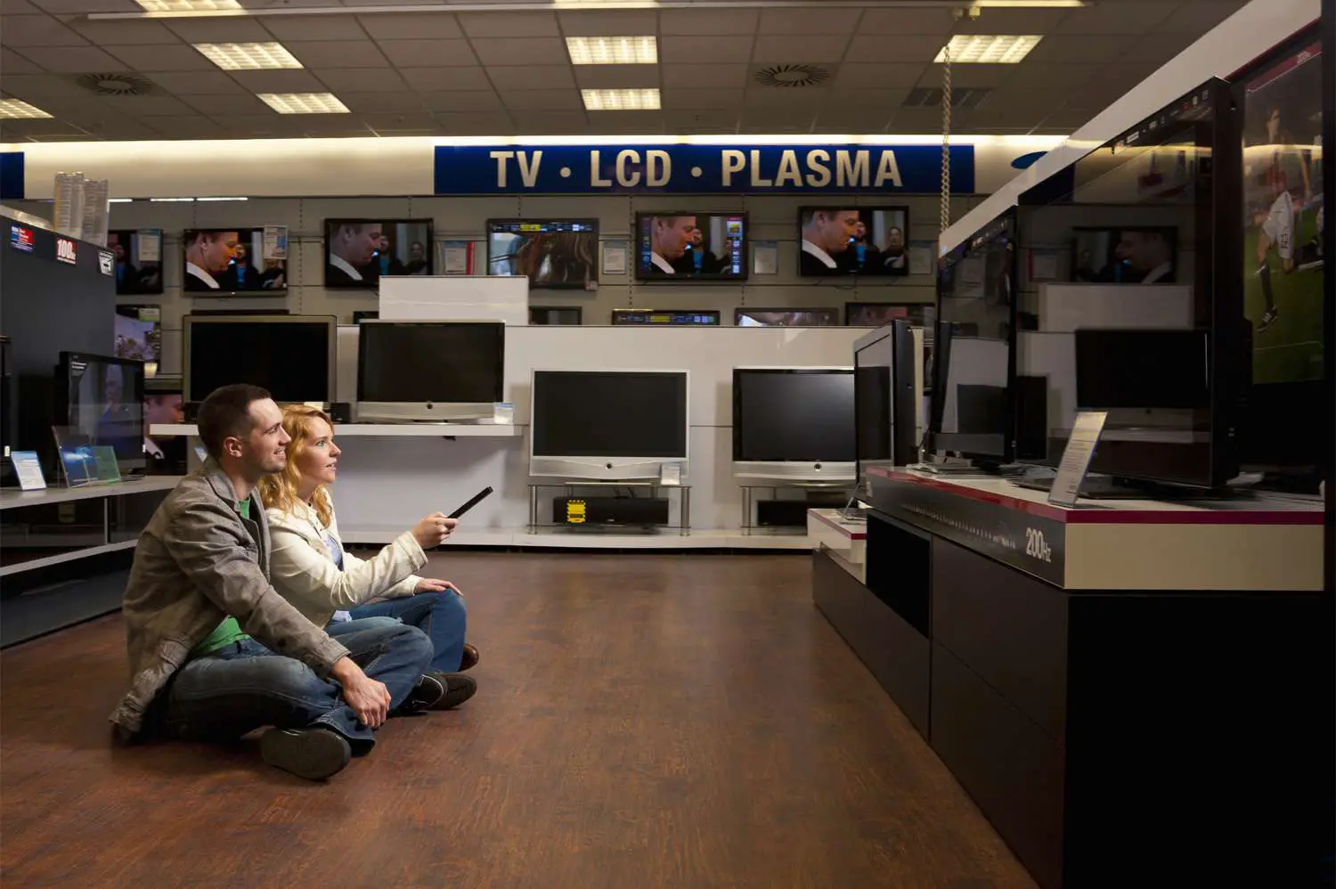 Casal verificando TVs: LCD x plasma