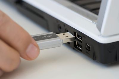 Pessoa conectando um pendrive USB em um laptop