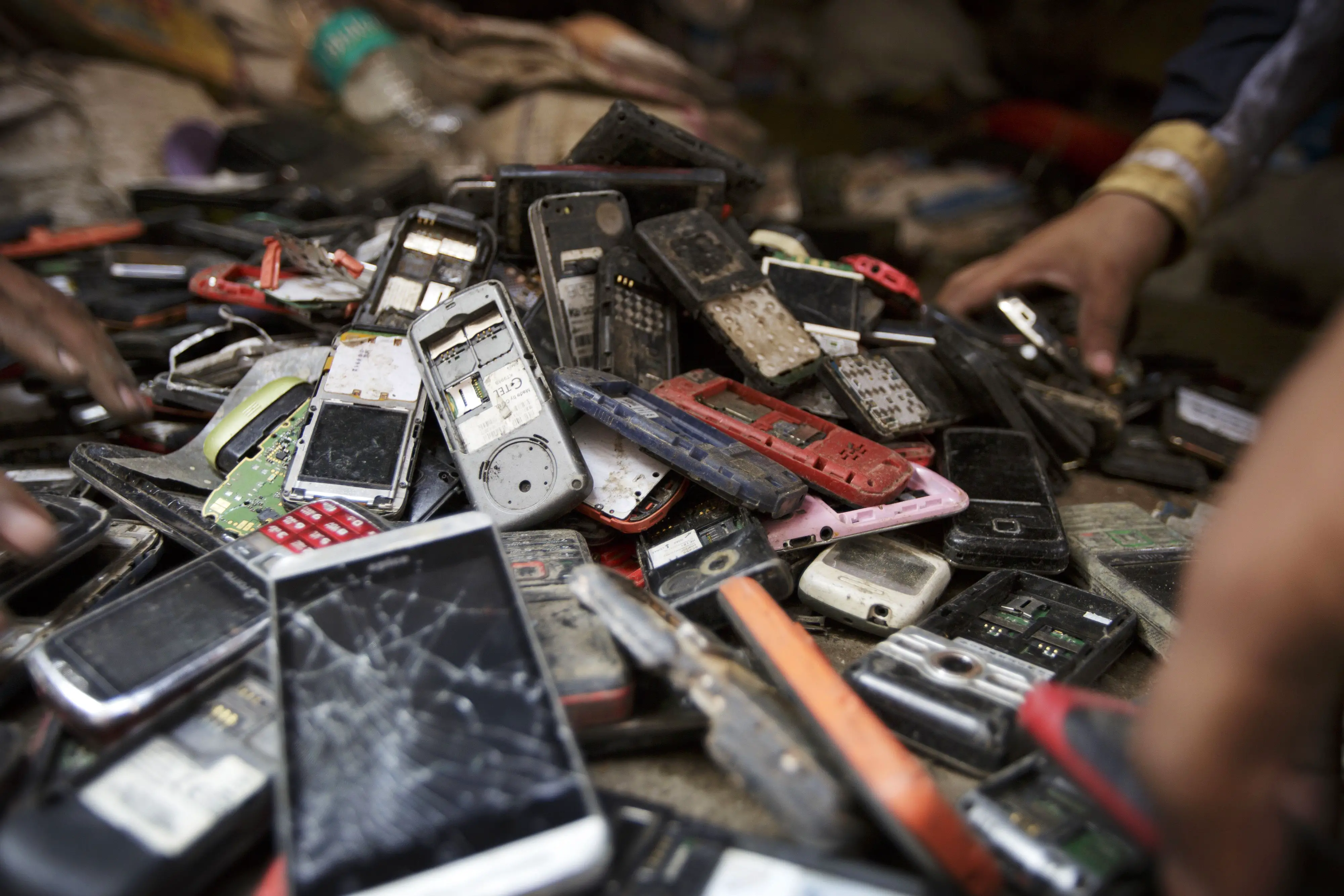 Trabalhadores vasculham uma pilha de telefones celulares usados ​​em Nova Delhi, Índia