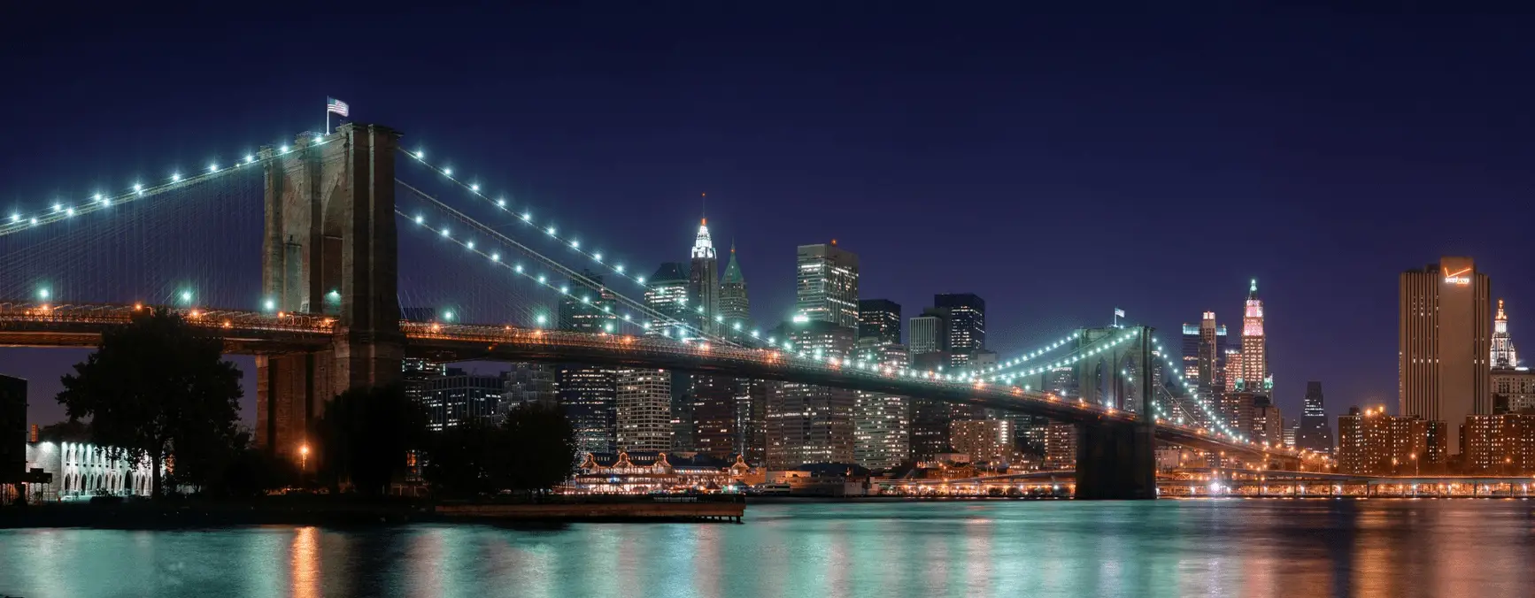 Imagem noturna de uma ponte iluminada contra um fundo da cidade do site de papel de parede panorâmico HDWallpapers
