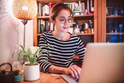 Jovem mulher asiática trabalhando em um laptop em casa