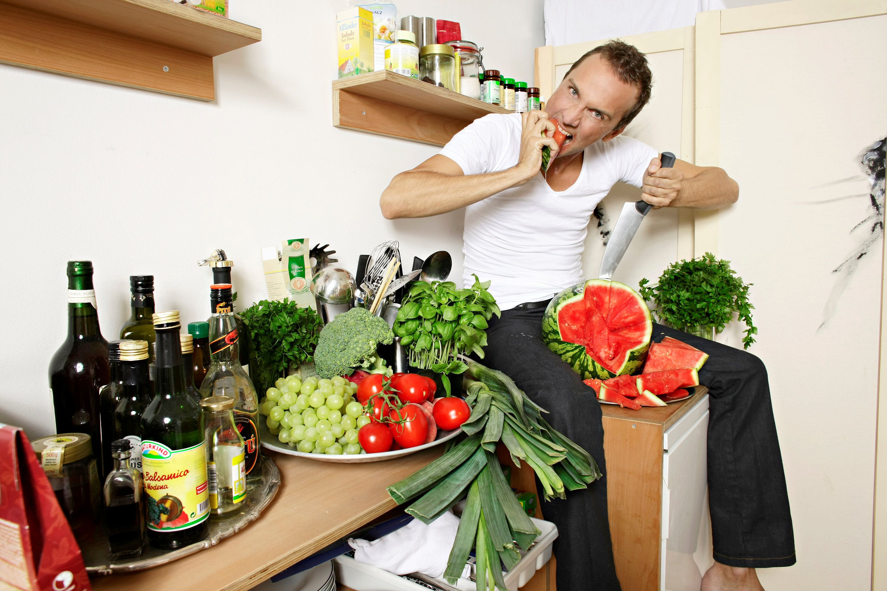 Homem sentado no balcão da cozinha com produtos e mantimentos