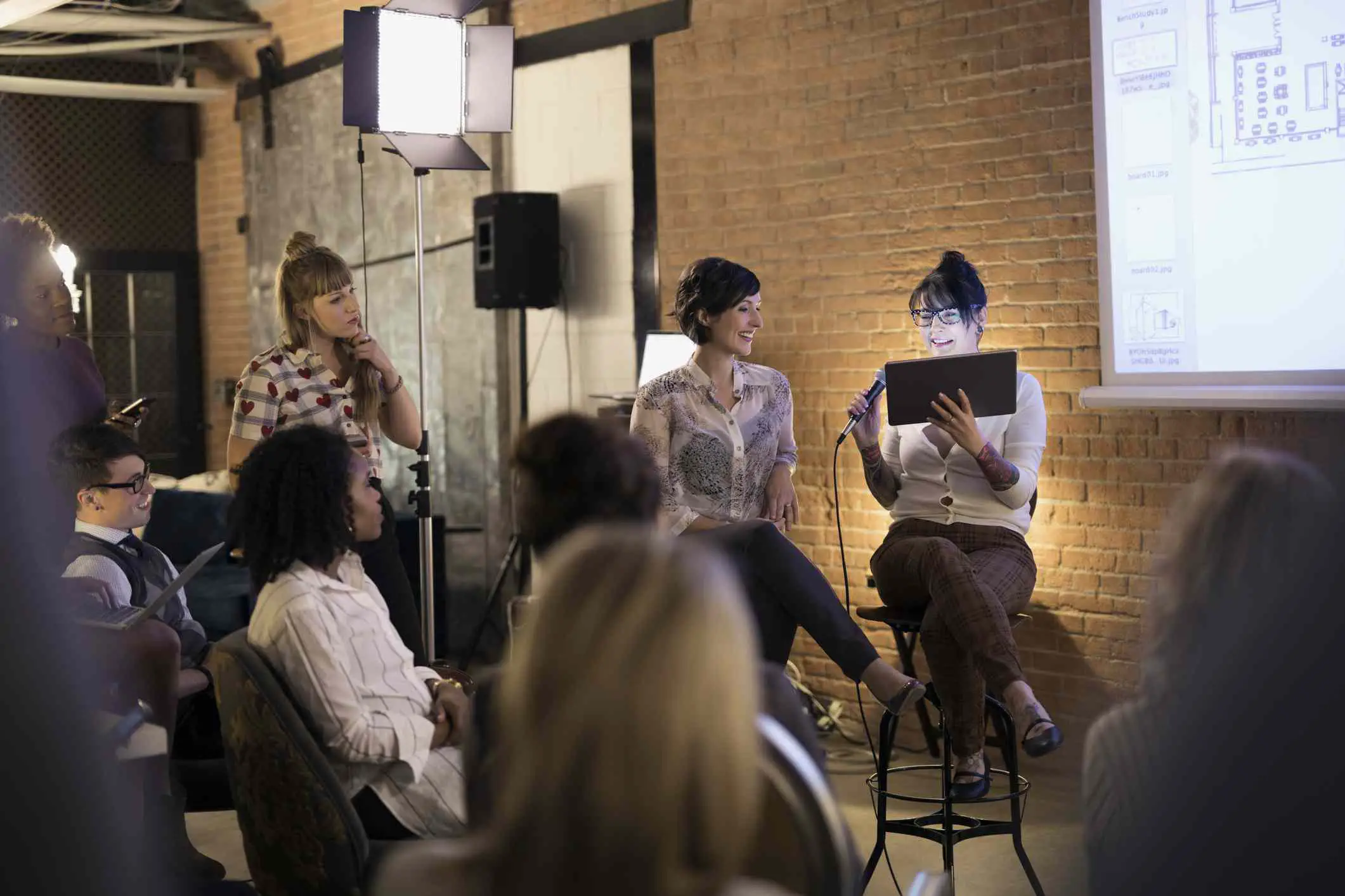 Designers femininas com microfone e tablet digital lideram a reunião da conferência