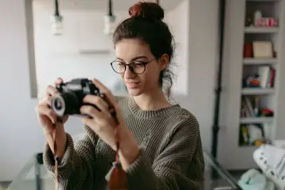 Jovem fotógrafo usando câmera em apartamento