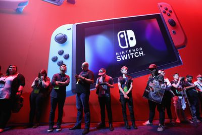 Pessoas em frente a uma imagem do Nintendo Switch.