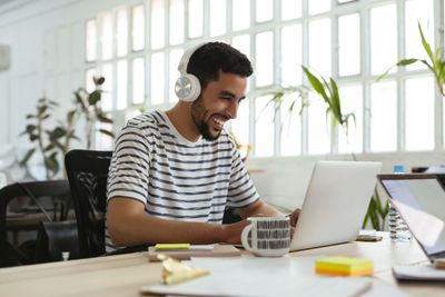 Pessoa usando fones de ouvido e usando um computador enquanto sorri