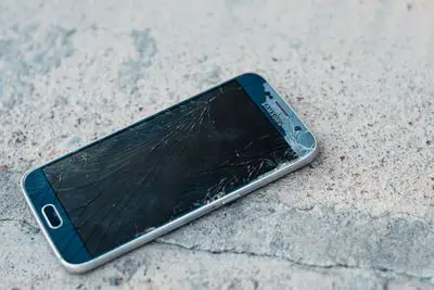 Um telefone Samsung Android azul no concreto com uma tela quebrada. 