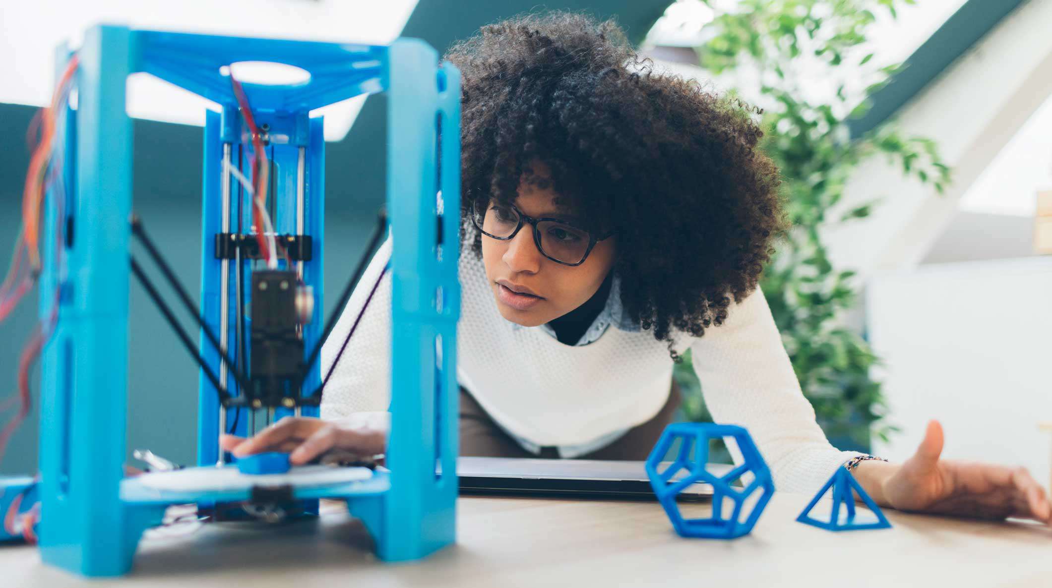 Fabricante assistindo uma impressora 3D construir uma peça
