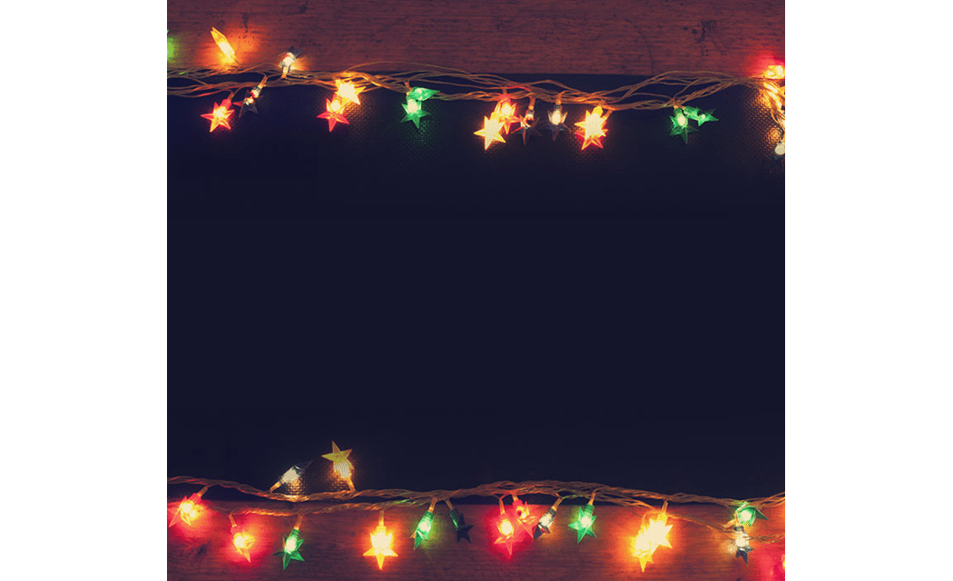 Artigos de papelaria por e-mail com luzes de Natal em uma mesa de madeira.